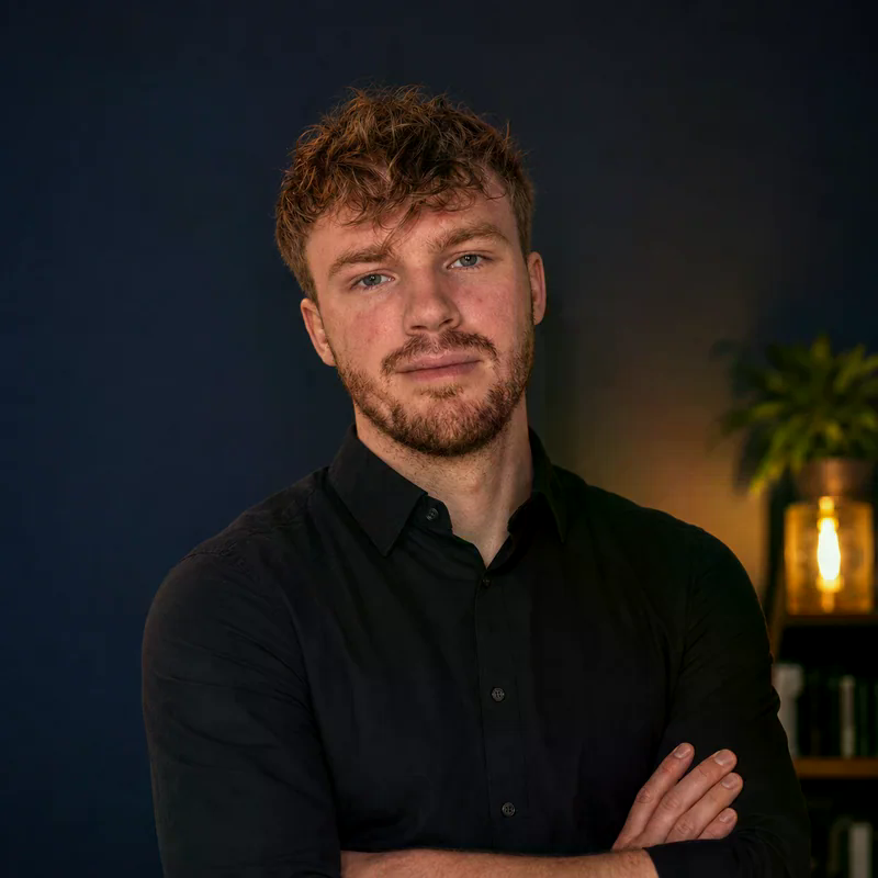 Philipp Steglich, Porträt in dunklem Hemd vor dunkelblauem Hintergrund